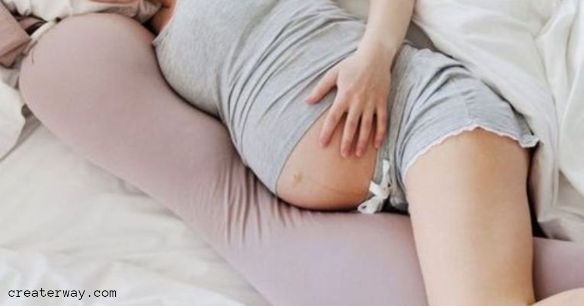 A women with pregnancy with her hand on wombs lying in a maternity pillow