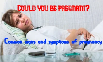 A woman lying on a couch, appearing unwell and holding her abdomen, with the text 'Could You Be Pregnant? Common signs and symptoms of pregnancy' overlayed on the image.